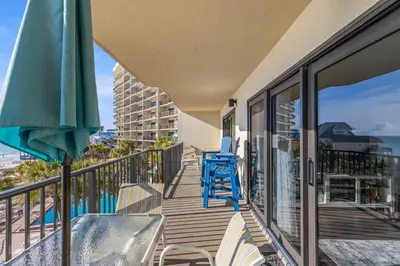 a balcony with chairs and an umbrella and the ocean at Commodore 0403 in Panama City Beach