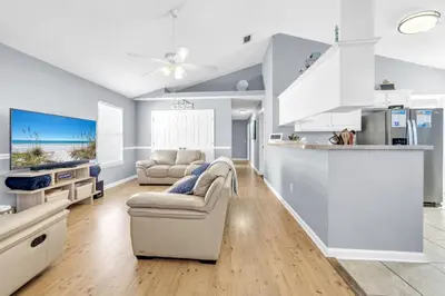 a living room with a couch and a kitchen at Jade Shell in Panama City Beach