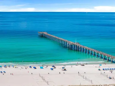 a pier over a beach with people in the water at Pet Friendly Beach House - Beachside Sunrise in Panama City Beach