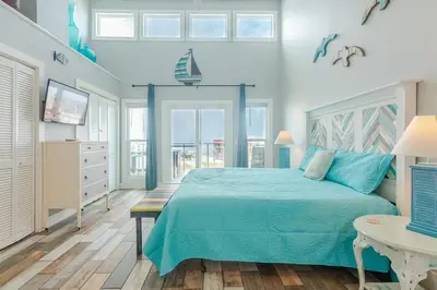 a bedroom with a blue bed and a television at Emerald Seascape! Gulf front! Dog friendly! in Panama City Beach