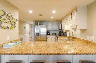 a kitchen with white cabinets and a granite counter top at Emerald Seascape! Gulf front! Dog friendly! in Panama City Beach