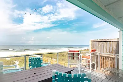 a deck with chairs and a table and the ocean at Emerald Seascape! Gulf front! Dog friendly! in Panama City Beach
