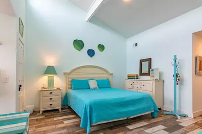 a bedroom with a blue bed and a white wall at Emerald Seascape! Gulf front! Dog friendly! in Panama City Beach