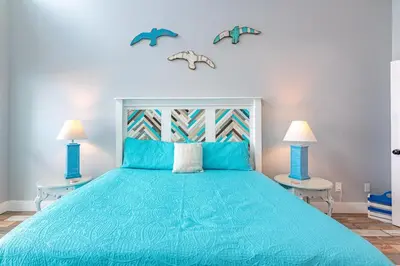 a bedroom with a blue bed with two tables at Emerald Seascape! Gulf front! Dog friendly! in Panama City Beach