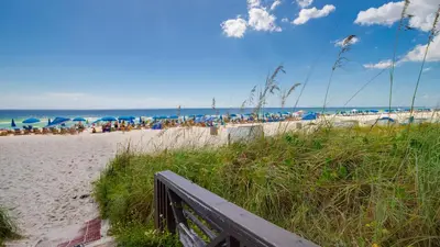 a sandy beach with umbrellas and people on the beach at Looking for a Shore Thing? Here it is! 2BR 25BA Sleeps 8! Beachfront! in Panama City Beach