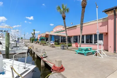 a marina with boats docked in front of a pink building at Looking for a Shore Thing? Here it is! 2BR 25BA Sleeps 8! Beachfront! in Panama City Beach