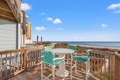 a balcony with a table and chairs and the ocean at GO-JO Getaway! Coastal Comfort, 2BR Beachfront Townhouse, Sleeps 6 in Panama City Beach