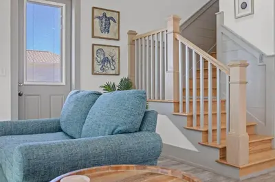 a living room with a blue chair and stairs at Keep Calm & Pool On at Peaceful Easy Feeling! Sleeps 20! in Panama City Beach