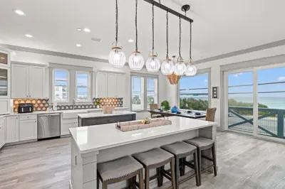 a kitchen with white cabinets and a large island with bar stools at Keep Calm & Pool On at Peaceful Easy Feeling! Sleeps 20! in Panama City Beach