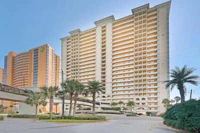 a large building with palm trees in front of it at Splash, Relax & Repeat at Dolphin View Retreat! Beachfront! Sleeps 9! in Panama City Beach