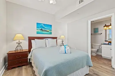 a white bedroom with a bed and a bathroom at Splash, Relax & Repeat at Dolphin View Retreat! Beachfront! Sleeps 9! in Panama City Beach