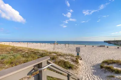 a sandy beach with a bench and the ocean at Come enjoy some Seawaves! 2BR 25BA Sleeps 8! Coastal Townhome w/Beachview! in Panama City Beach