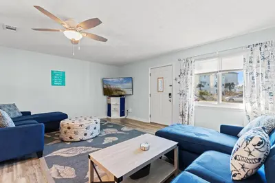 a living room with a blue couch and a table at Stay at The Salty Palm! 2BR 15BA Sleeps 7 in Panama City Beach