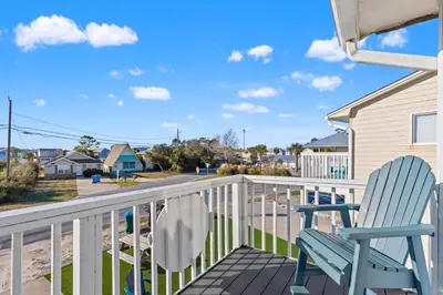 a blue rocking chair sitting on a balcony with a street at Stay at The Salty Palm! 2BR 15BA Sleeps 7 in Panama City Beach