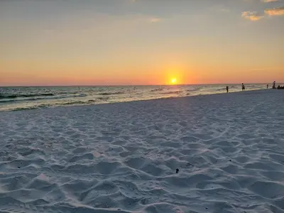 a beach with the sun setting in the ocean at Seas the Day! Your Perfect 2BR Beachfront Escape! Sleeps 8! in Panama City Beach