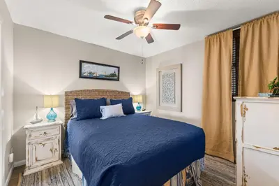 a bedroom with a blue bed and a ceiling fan at Beachfront! Balcony Views! Pools and Beach Access in Panama City Beach