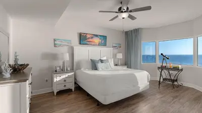a white bedroom with a bed and a ceiling fan at Tidewater Horizon by Avantstay Beachfront Condo Indoor Pool Spa Amenities Movie Theater Near Pier Park in Panama City Beach