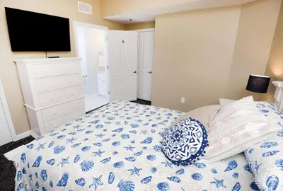 a bedroom with a blue and white bed and a tv at Shores of Panama 530 in Panama City Beach