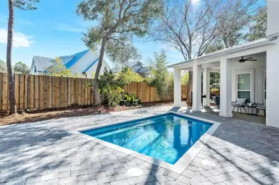 a swimming pool in a backyard with a fence at Where Waters Meet by Travel Life Vacations in Watersound Beach