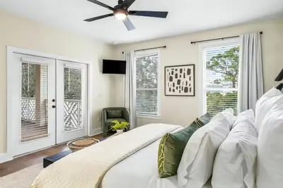 a bedroom with a white bed with a ceiling fan at Where Waters Meet by Travel Life Vacations in Watersound Beach