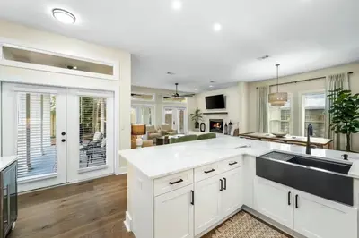 a kitchen with white cabinets and a large island at Where Waters Meet by Travel Life Vacations in Watersound Beach