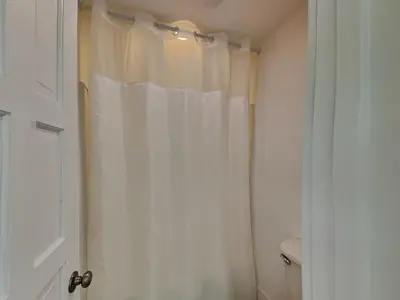 a bathroom with a shower with a white shower curtain at Tiki Tango Hideaway in Panama City Beach