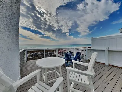 a balcony with a table and chairs on the beach at Tiki Tango Hideaway in Panama City Beach