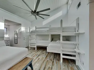 a bedroom with white bunk beds and a ceiling fan at Tiki Tango Hideaway in Panama City Beach