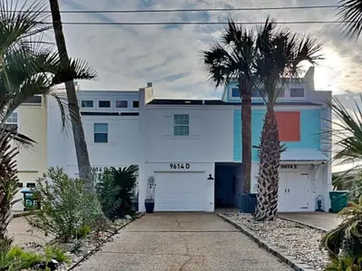 a white house with palm trees in front of it at Tiki Tango Hideaway in Panama City Beach