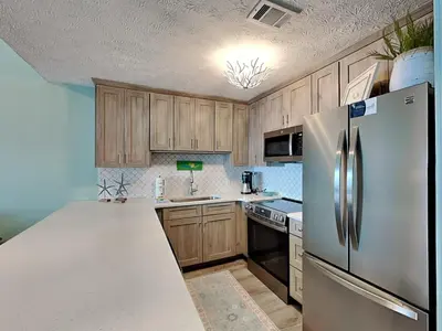 a kitchen with wooden cabinets and a stainless steel refrigerator at Southwind I Condo #K8 in Panama City Beach