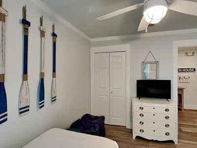 a room with a tv and a dresser with baseball bats on the wall at Cassine Gardens #101 in Seagrove Beach