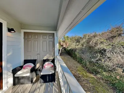 a porch with two chairs and a view of a road at Cassine Gardens #101 in Seagrove Beach