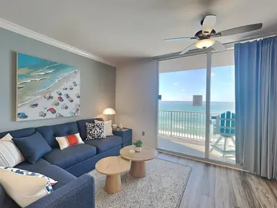 a living room with a blue couch and a view of the ocean at Tidewater Beach Resort #503 in Panama City Beach