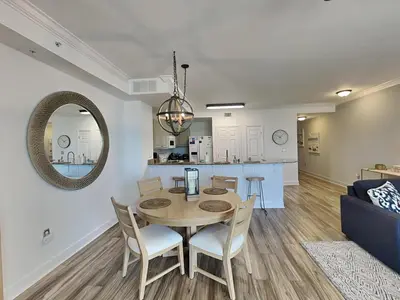 a dining room and living room with a table and chairs at Tidewater Beach Resort #503 in Panama City Beach