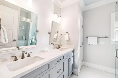 a white bathroom with two sinks and a shower at Casablanca By The Sea by 30A Escapes in Rosemary Beach