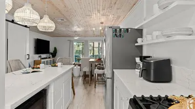 a kitchen with white counter tops and a dining room at Sandbar Serenade by AvantStay Beachside Home Pool Tennis Court Beach Access Near Pier Park in Panama City Beach