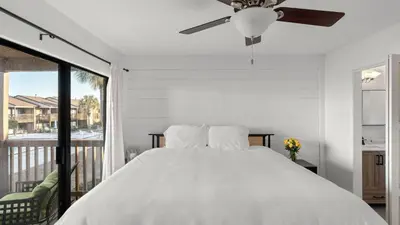 a white bedroom with a bed and a balcony at Sandbar Serenade by AvantStay Beachside Home Pool Tennis Court Beach Access Near Pier Park in Panama City Beach