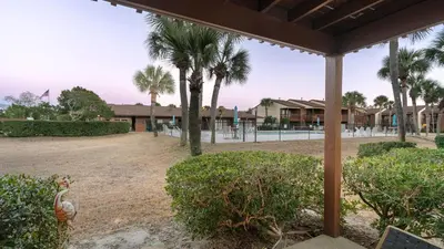 a view of a yard with palm trees and a building at Sandbar Serenade by AvantStay Beachside Home Pool Tennis Court Beach Access Near Pier Park in Panama City Beach