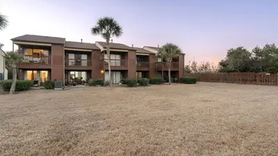 a house with palm trees in front of a yard at Sandbar Serenade by AvantStay Beachside Home Pool Tennis Court Beach Access Near Pier Park in Panama City Beach