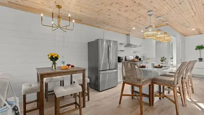 a kitchen with a refrigerator and a table and chairs at Sandbar Serenade by AvantStay Beachside Home Pool Tennis Court Beach Access Near Pier Park in Panama City Beach