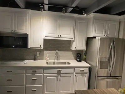 a kitchen with white cabinets and a stainless steel refrigerator at Tiny home living!! First floor condo! in Panama City Beach
