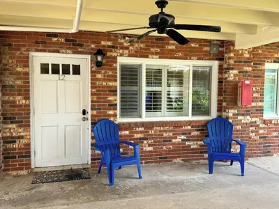 two blue chairs sitting in front of a brick house at Tiny home living!! First floor condo! in Panama City Beach