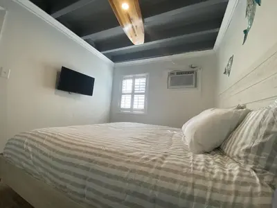 a bedroom with a bed and a television on the wall at Tiny home living!! First floor condo! in Panama City Beach