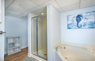 a bathroom with a bath tub and a picture of a cat on the wall at Emerald Beach 2030 by Emerald Coast Retreats in Panama City Beach