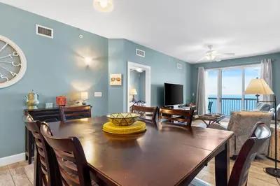a dining room with a table and chairs and a living room at Sunrise Beach 17th Floor 3BR Condo | Oversized Balcony, Heated Pool, Near Pier Park in Panama City Beach