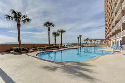 a swimming pool with palm trees and a building at Sunrise Beach 17th Floor 3BR Condo | Oversized Balcony, Heated Pool, Near Pier Park in Panama City Beach
