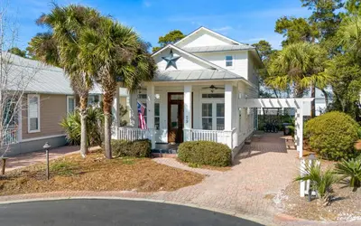 a white house with palm trees in front of it at 30A Stars and Stripes in Seagrove Beach