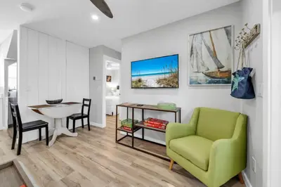 a living room with a green chair and a table at Pelican's Roost in Santa Rosa Beach