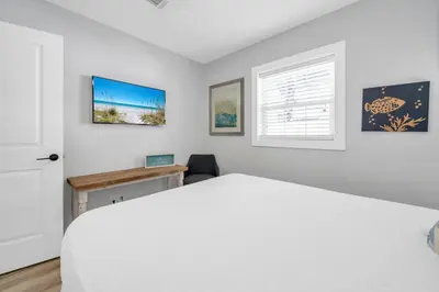 a bedroom with a white bed and a desk at Pelican's Roost in Santa Rosa Beach