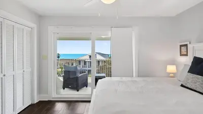 a bedroom with a bed and a view of the ocean at Sandy Pelican by AvantStay Exclusive Beach Access Private Pool Firepit Balcony Sunset Views in Seacrest